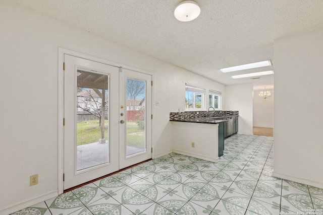 kitchen featuring a textured ceiling, a skylight, french doors, and sink