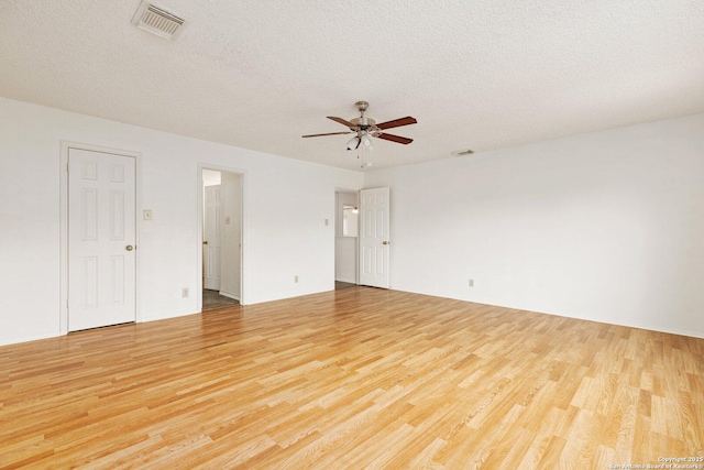 empty room with a textured ceiling, ceiling fan, and light hardwood / wood-style flooring