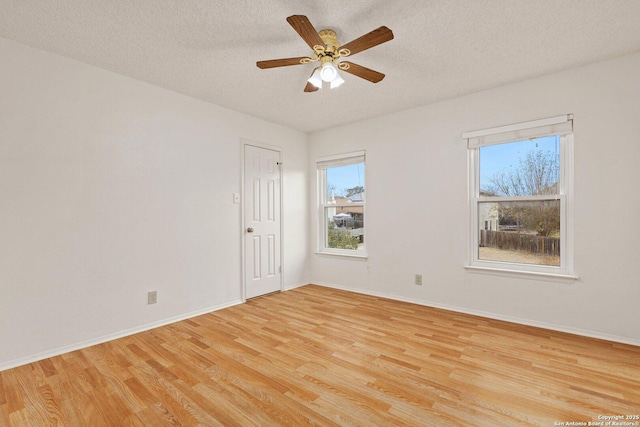 empty room featuring a textured ceiling, plenty of natural light, and light hardwood / wood-style flooring