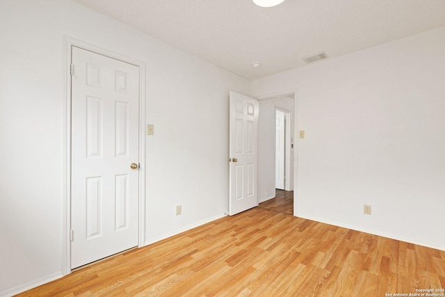 unfurnished room featuring a textured ceiling and light wood-type flooring