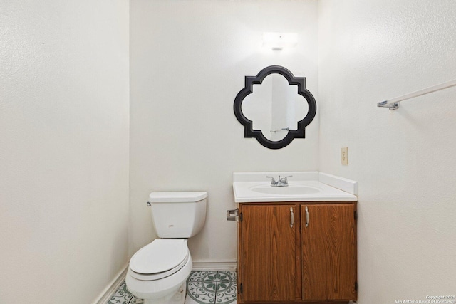 bathroom with toilet, vanity, and tile patterned flooring