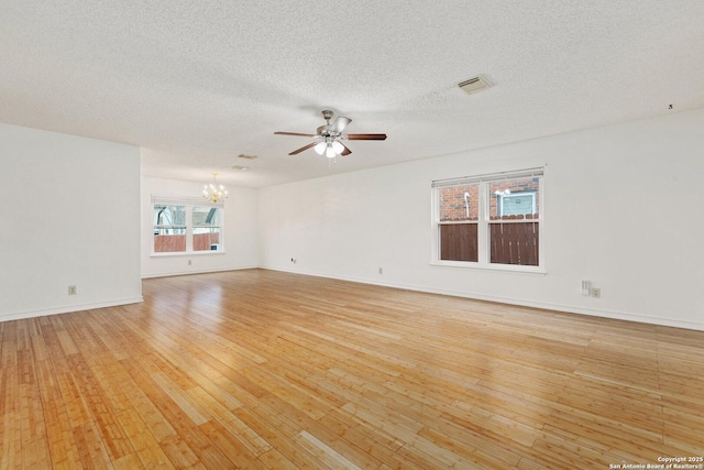 unfurnished room featuring a textured ceiling, light hardwood / wood-style flooring, and ceiling fan with notable chandelier