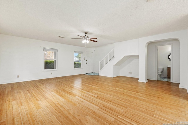 unfurnished living room with a textured ceiling, ceiling fan, and light hardwood / wood-style flooring