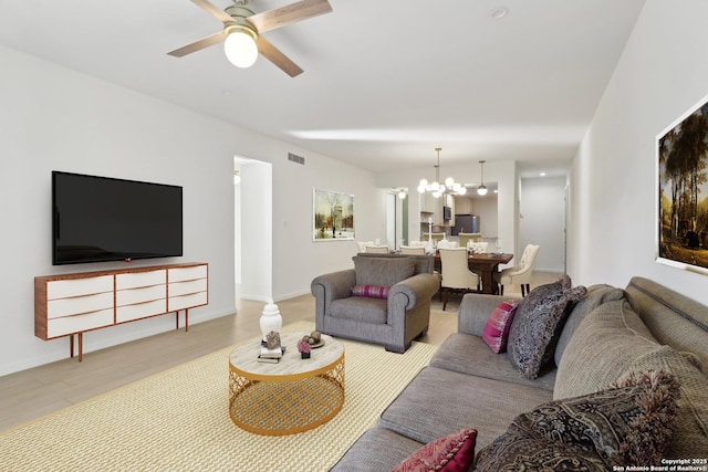 living room featuring ceiling fan with notable chandelier and light wood-type flooring