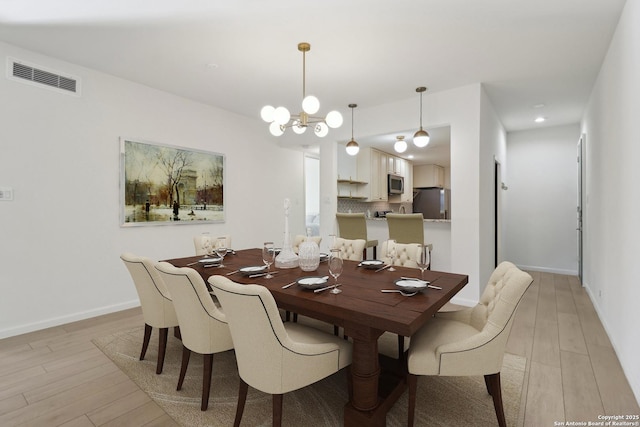 dining area with an inviting chandelier and light hardwood / wood-style flooring