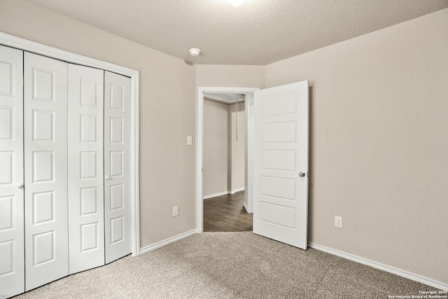 unfurnished bedroom featuring carpet floors, a textured ceiling, and a closet