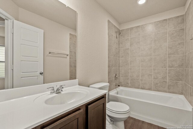 full bathroom featuring hardwood / wood-style floors, vanity, toilet, and tiled shower / bath