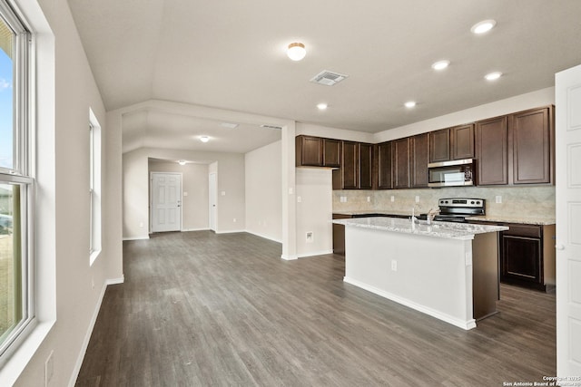 kitchen featuring a wealth of natural light, stainless steel appliances, an island with sink, decorative backsplash, and dark brown cabinets