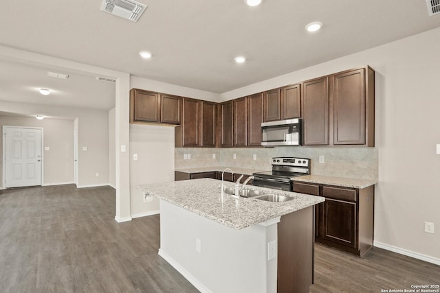 kitchen with dark wood-type flooring, a kitchen island with sink, sink, tasteful backsplash, and stainless steel appliances