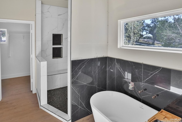 bathroom with hardwood / wood-style floors, separate shower and tub, and tile walls