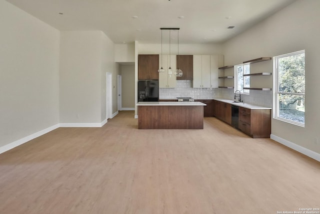 kitchen with light wood-style flooring, a center island, black appliances, open shelves, and backsplash