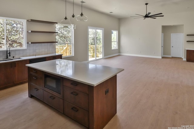 kitchen with sink, ceiling fan, tasteful backsplash, decorative light fixtures, and a kitchen island