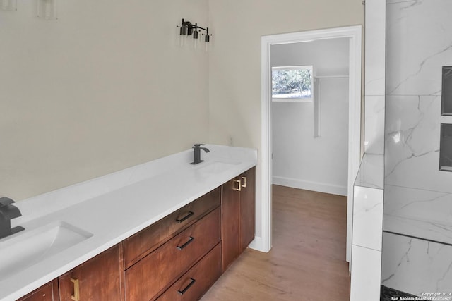 full bathroom with double vanity, a sink, and wood finished floors