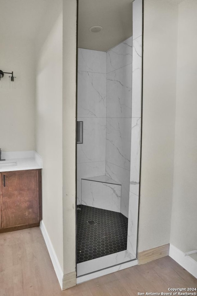 full bath featuring a stall shower, wood finished floors, vanity, and baseboards