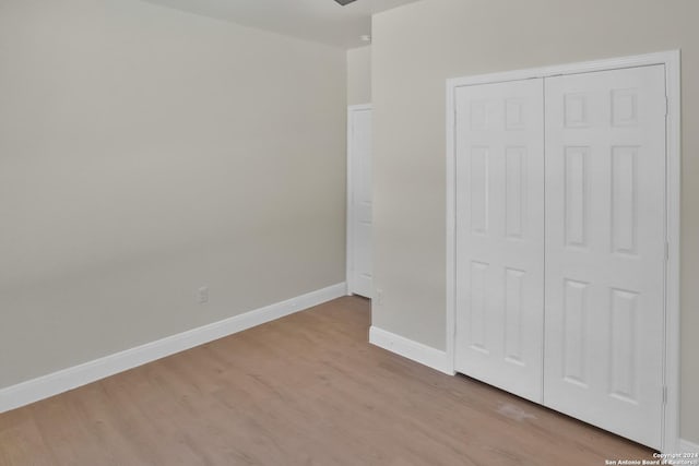 unfurnished bedroom with light wood-type flooring, a closet, and baseboards