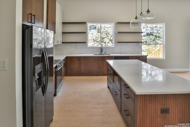 kitchen with open shelves, appliances with stainless steel finishes, a sink, and a center island