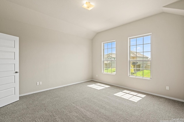 carpeted empty room with vaulted ceiling