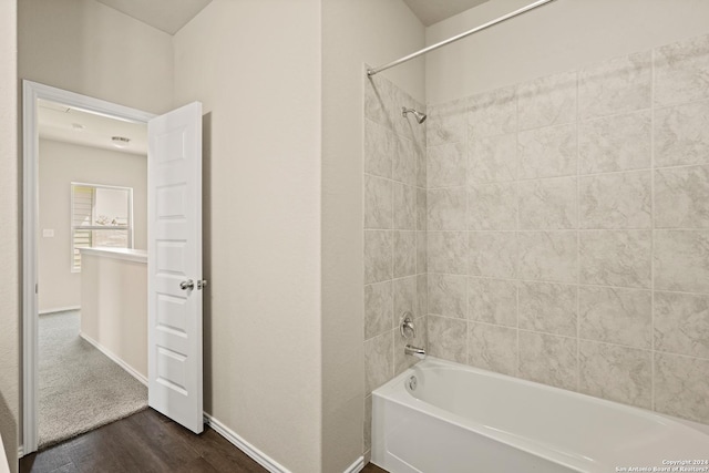 bathroom with hardwood / wood-style floors and tiled shower / bath