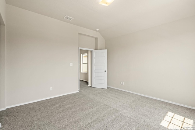 unfurnished room featuring carpet and vaulted ceiling