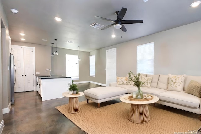 living room featuring ceiling fan, sink, and plenty of natural light