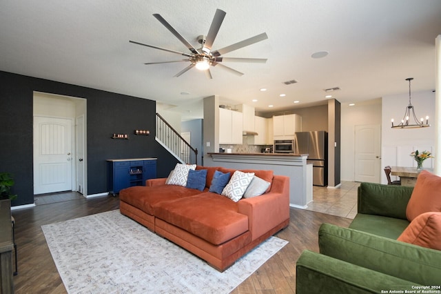 living room featuring wood-type flooring and ceiling fan with notable chandelier