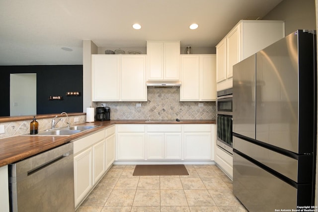 kitchen with sink, light tile patterned floors, tasteful backsplash, white cabinets, and appliances with stainless steel finishes