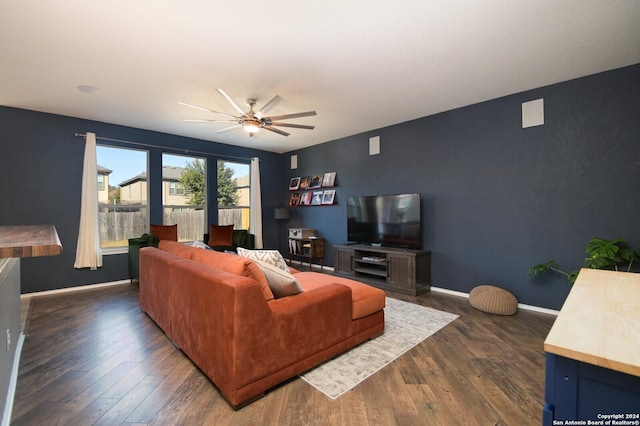 living room with ceiling fan and dark wood-type flooring