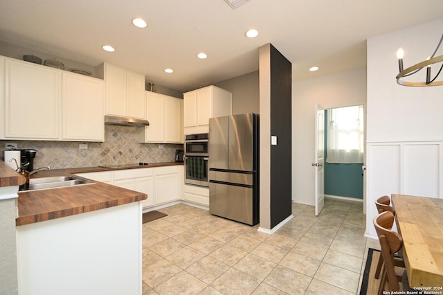 kitchen featuring wood counters, backsplash, stainless steel appliances, sink, and white cabinetry