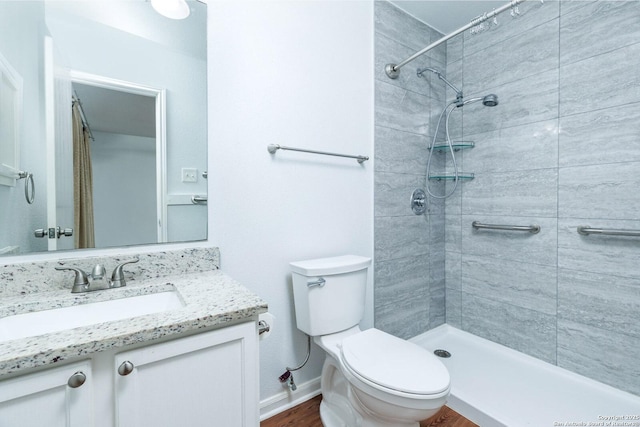 bathroom featuring a tile shower, vanity, and toilet