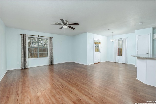 unfurnished living room with hardwood / wood-style floors and ceiling fan with notable chandelier