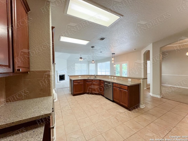 kitchen featuring dishwasher, sink, hanging light fixtures, light tile patterned floors, and kitchen peninsula