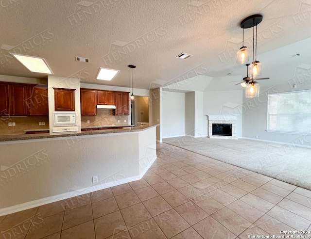 kitchen with hanging light fixtures, tasteful backsplash, white microwave, a textured ceiling, and light tile patterned floors