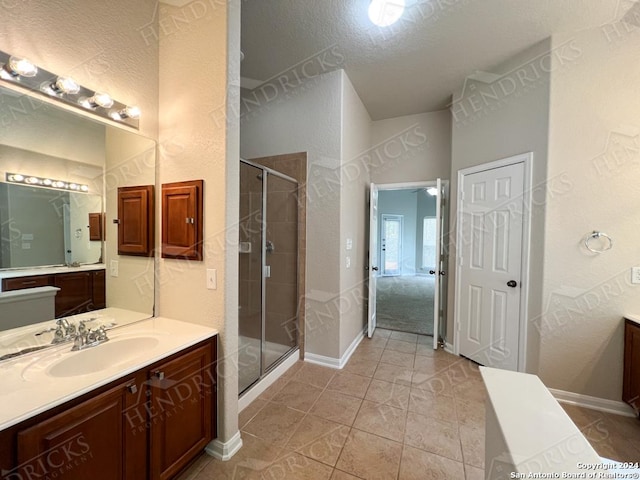 bathroom with tile patterned floors, vanity, an enclosed shower, and a textured ceiling