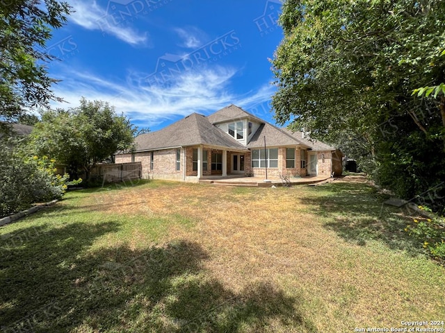 back of property with a yard and a patio