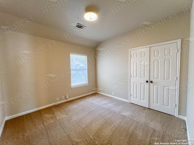 unfurnished bedroom with carpet flooring, a closet, and a textured ceiling