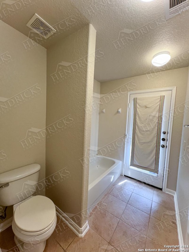 bathroom with tile patterned floors, a textured ceiling, and toilet