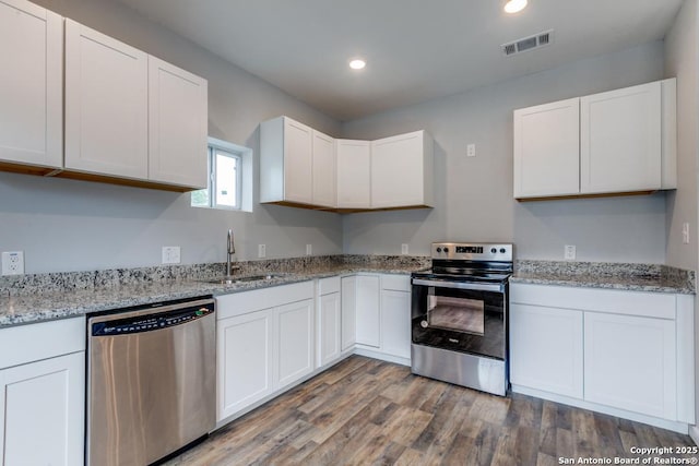 kitchen with light stone countertops, white cabinetry, sink, stainless steel appliances, and light hardwood / wood-style floors