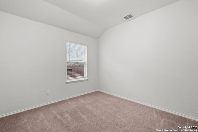 carpeted empty room featuring lofted ceiling