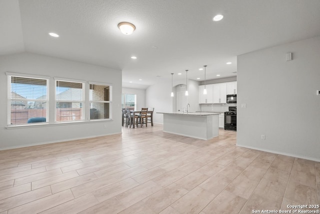 unfurnished living room featuring a textured ceiling, lofted ceiling, and sink