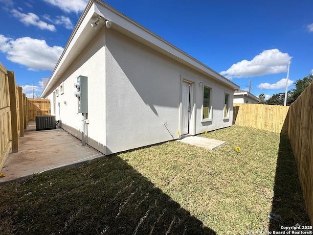 back of house featuring central AC unit, a patio area, and a lawn