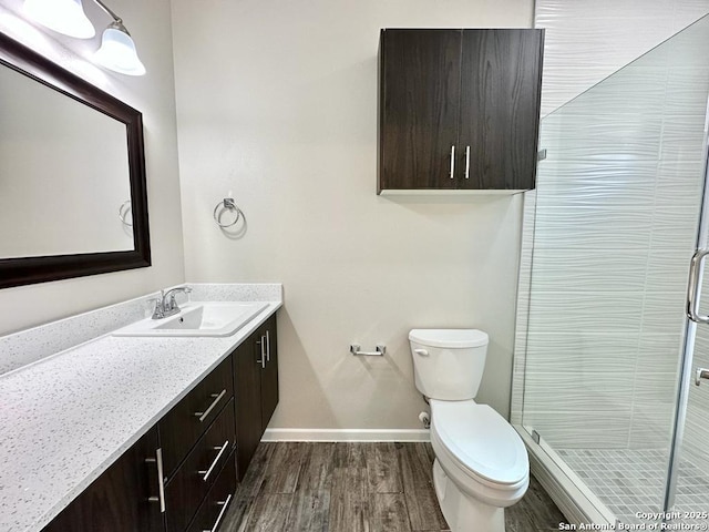 bathroom featuring a shower with door, vanity, and toilet