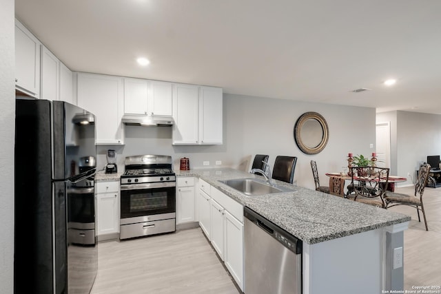 kitchen with sink, light wood-type flooring, stainless steel appliances, white cabinets, and light stone counters