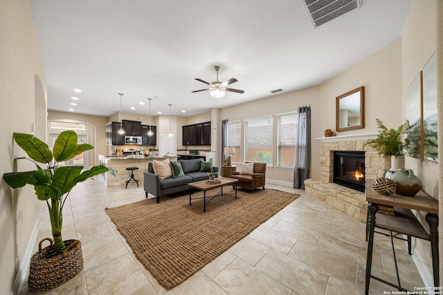 living room featuring ceiling fan and a fireplace