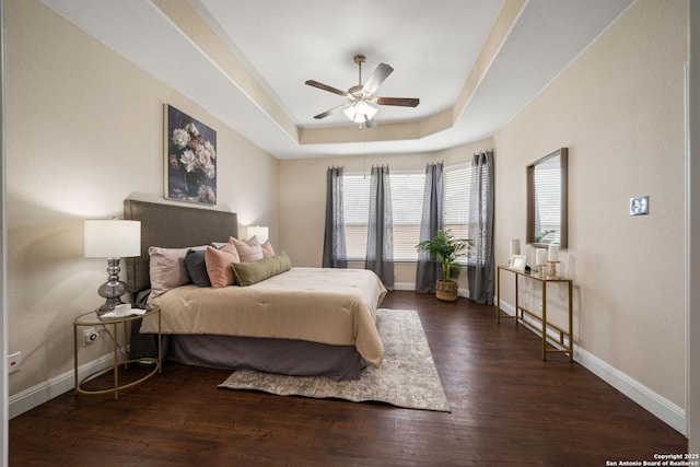 bedroom featuring a tray ceiling, ceiling fan, and dark wood-type flooring