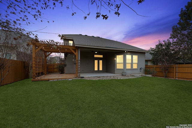 back house at dusk with a lawn, a pergola, and a patio area