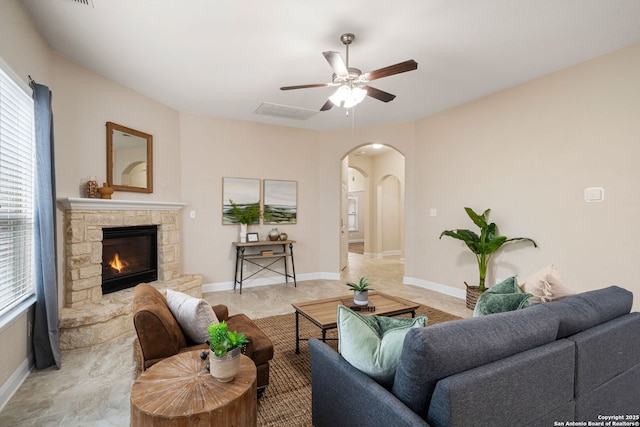 living room with ceiling fan and a stone fireplace