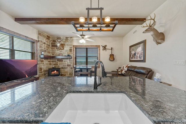 kitchen featuring beam ceiling, decorative light fixtures, ceiling fan, and sink