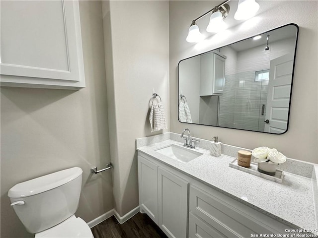 bathroom featuring hardwood / wood-style flooring, vanity, a shower with shower door, and toilet