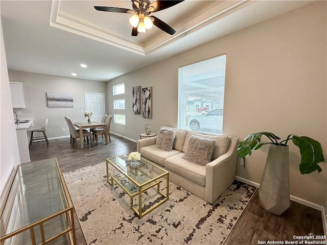 living room featuring a tray ceiling, ceiling fan, and dark hardwood / wood-style floors