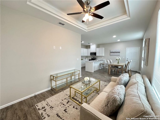 living room featuring a tray ceiling, ceiling fan, and dark hardwood / wood-style floors